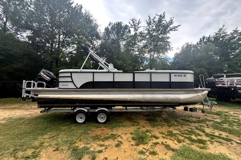 Slide: The Image of 2021 Bentley Pontoons 243 Navigator on trailer, surrounded by trees and grass. - 18