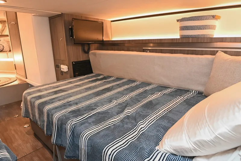 Slide: The Image of 2024 Sea Ray Sundancer 320 cabin interior with striped bedding and modern amenities. - 68