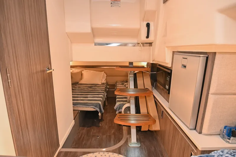 Slide: The Image of Interior of 2024 Sea Ray Sundancer 320, featuring cozy cabin with beds and kitchenette. - 61