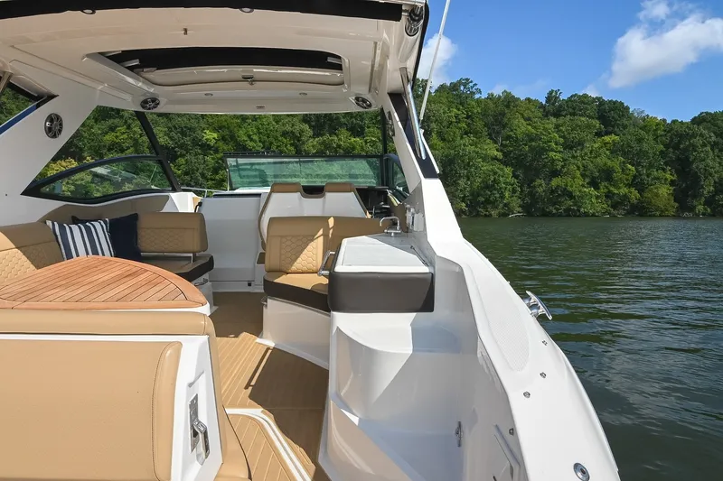 Slide: The Image of 2024 Sea Ray Sundancer 320 interior with luxurious seating on a serene lake. - 16