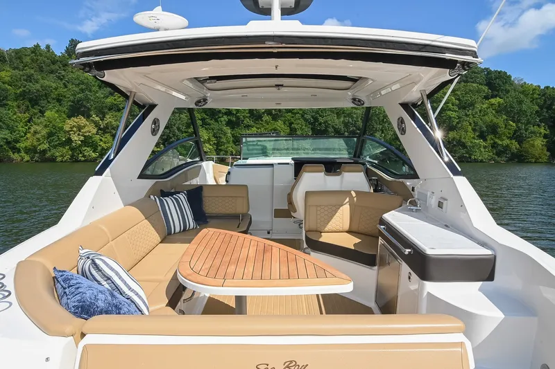 Slide: The Image of 2024 Sea Ray Sundancer 320 boat interior with luxurious seating and wooden table on a lake. - 15