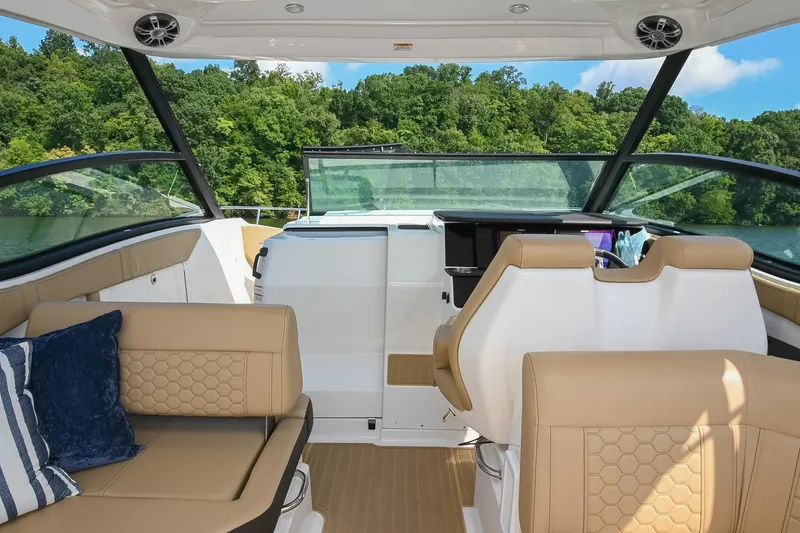 Slide: The Image of 2024 Sea Ray Sundancer 320 cockpit with tan seating and scenic lake view. - 31