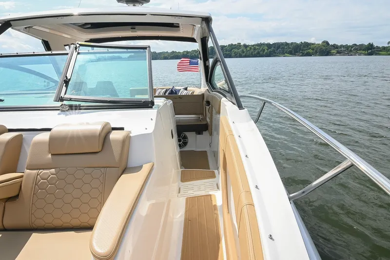 Slide: The Image of 2024 Sea Ray Sundancer 320 yacht interior with tan seating, cruising on a serene lake. - 27