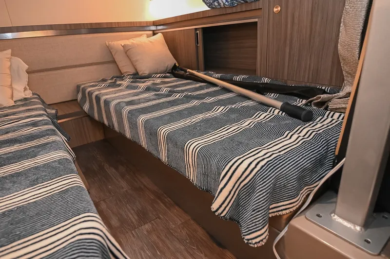 Slide: The Image of 2024 Sea Ray Sundancer 320 cabin interior with striped bedding and cozy pillows. - 67