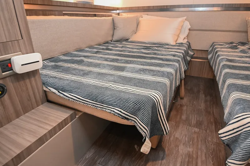 Slide: The Image of 2024 Sea Ray Sundancer 320 cabin interior with twin beds and striped bedding. - 66