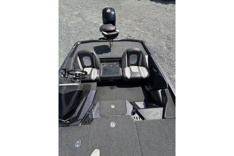 Slide: The Image of 2022 Ranger Z518 boat interior with dual seats and steering wheel on gravel surface. - 11