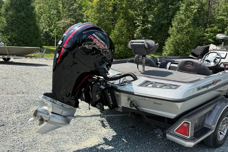 Slide: The Image of 2022 Ranger Z518 boat with Mercury Pro XS engine, parked on gravel, surrounded by trees. - 5
