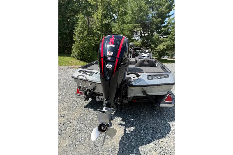 Slide: The Image of 2022 Ranger Z518 boat with powerful outboard motor, parked on gravel, surrounded by trees. - 6