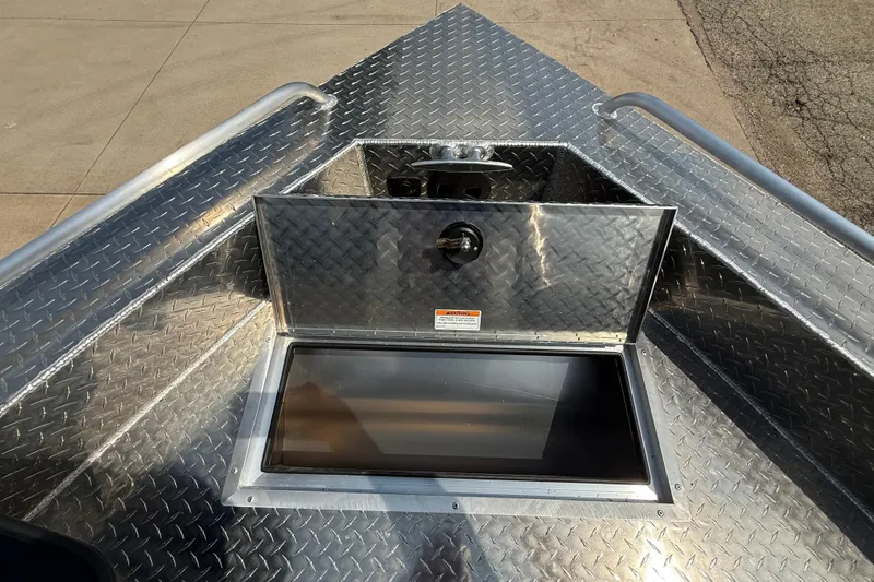 Slide: The Image of 2026 Lund 210 Heavy Gauge boat with open storage compartment on diamond plate deck. - 25