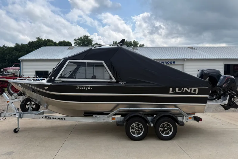 Slide: The Image of 2026 Lund 210 Heavy Gauge boat on trailer, covered and parked outdoors. - 38