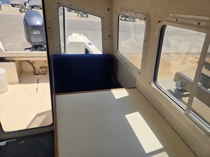 Slide: The Image of Interior of a 2002 C-Dory 22FT Cruiser with a table and blue seating. - 13
