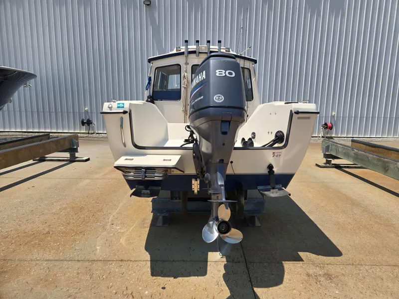 The Image of A 2002 C-Dory 22FT Cruiser with a Yamaha 80 outboard motor, parked on a concrete surface. - 0