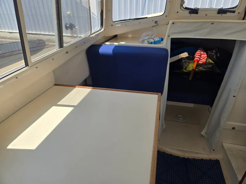 Slide: The Image of Interior of a 2002 C-Dory 22FT Cruiser with a table and blue seating. - 14