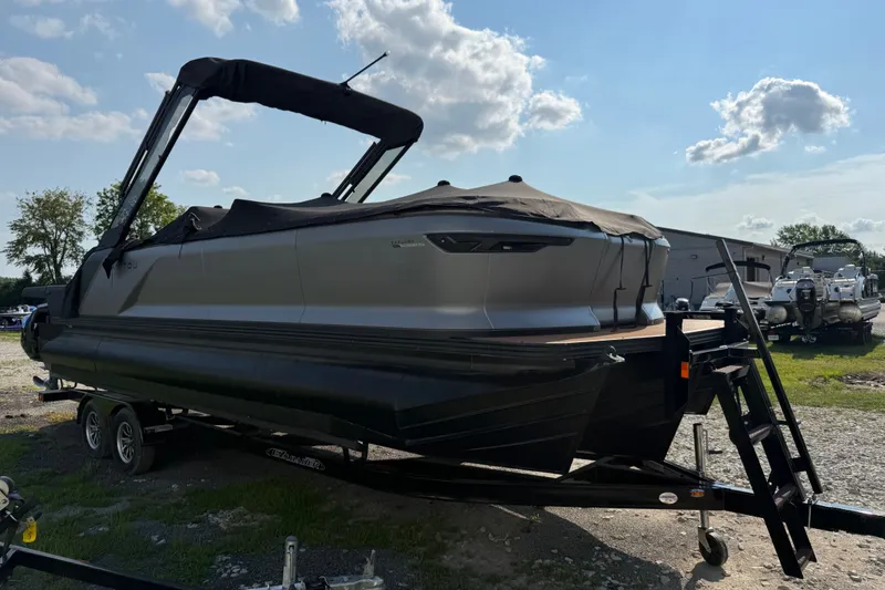 The Image of 2024 Manitou Explore Dual Engine boat on trailer under clear sky. - 0