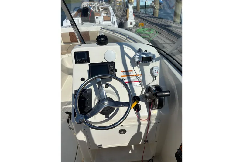 Slide: The Image of Helm of 2024 Cobia 220 Dual Console boat with steering wheel and controls. - 4