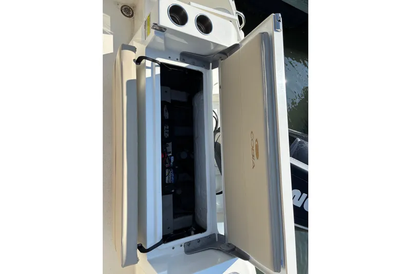 Slide: The Image of 2024 Cobia 220 Dual Console boat seat storage compartment with cup holders. - 9