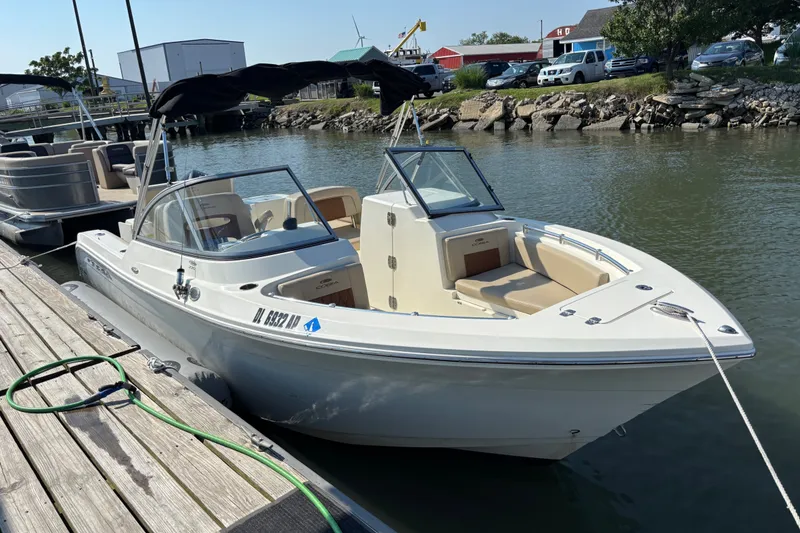 The Image of 2024 Cobia 220 Dual Console boat docked at a marina, featuring sleek design and comfortable seating. - 1