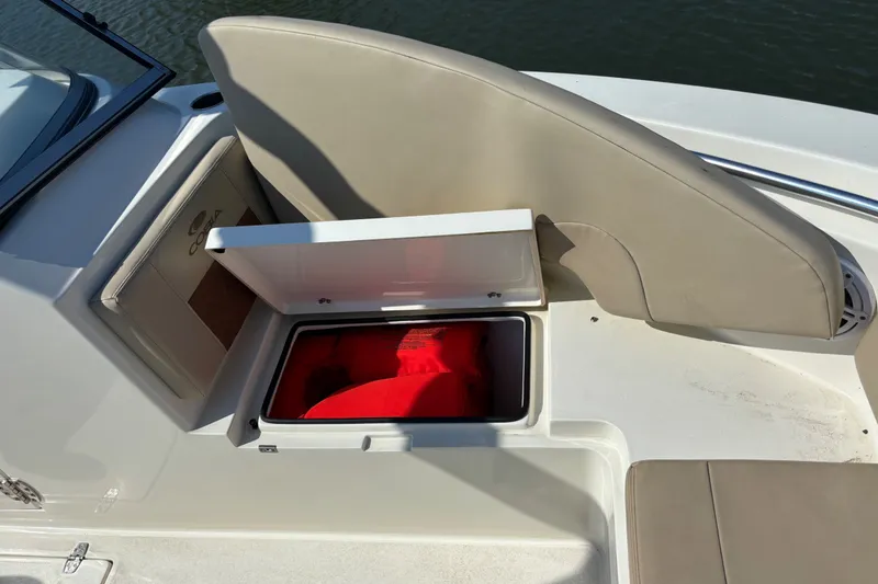 Slide: The Image of 2024 Cobia 220 Dual Console boat storage compartment with red life jackets. - 6
