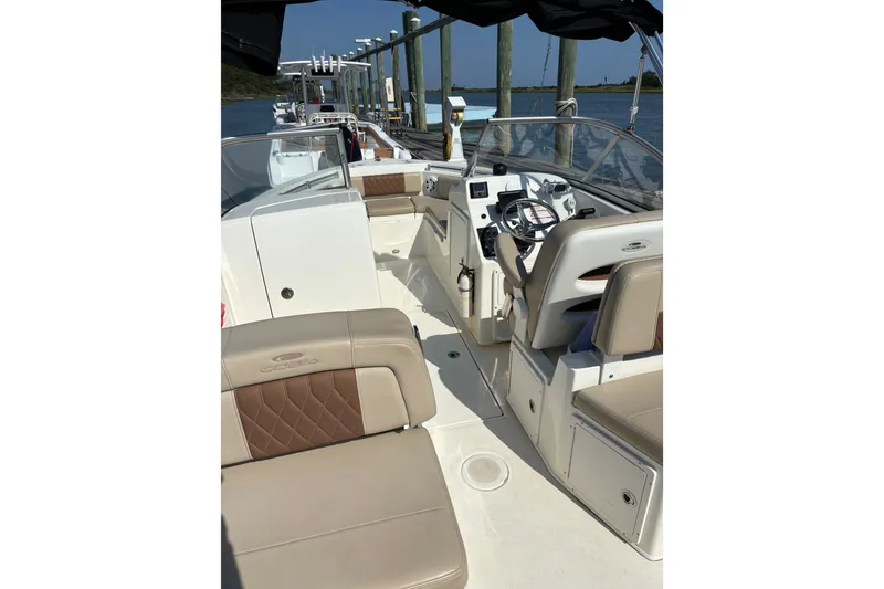Slide: The Image of 2024 Cobia 220 Dual Console boat interior with beige seating and steering console. - 7