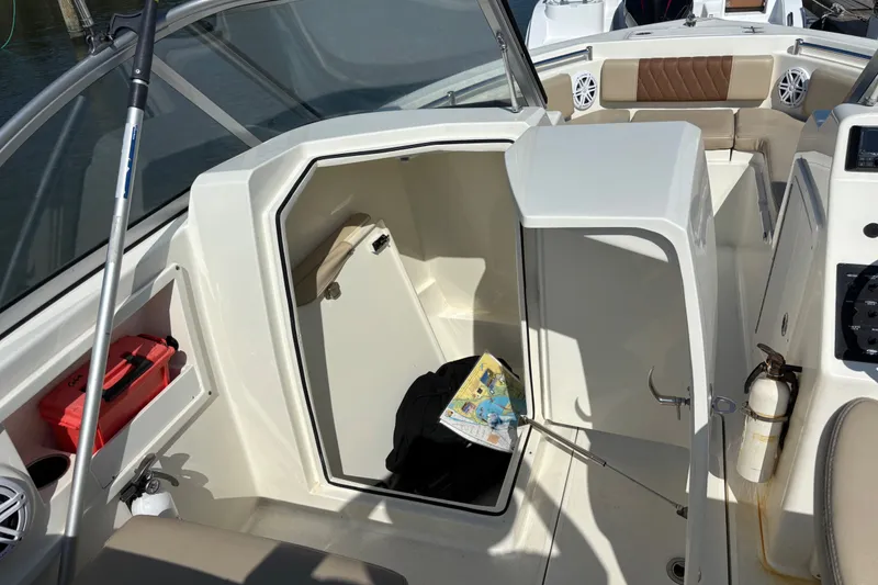 Slide: The Image of 2024 Cobia 220 Dual Console boat interior with storage compartment and seating area. - 10