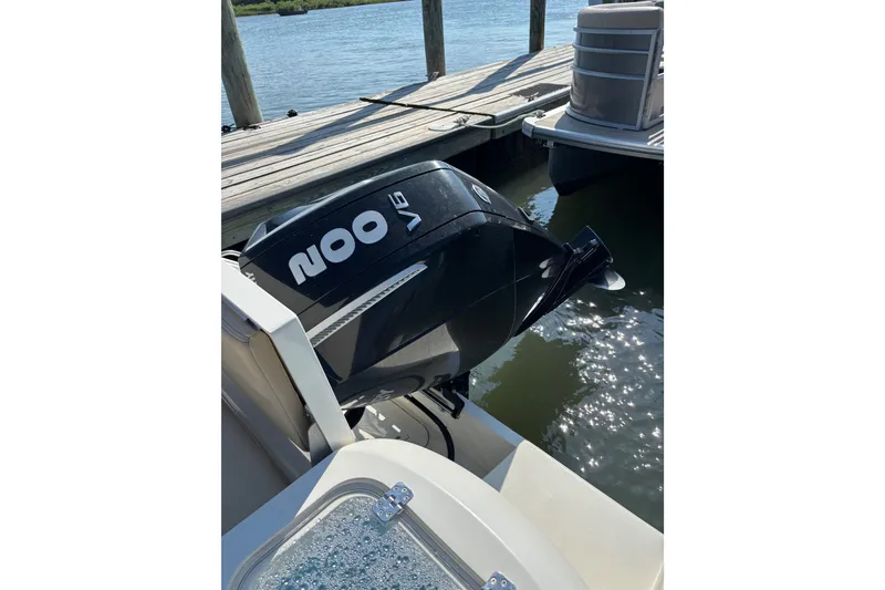 Slide: The Image of 2024 Cobia 220 Dual Console with powerful 200 V6 outboard engine docked by water. - 8