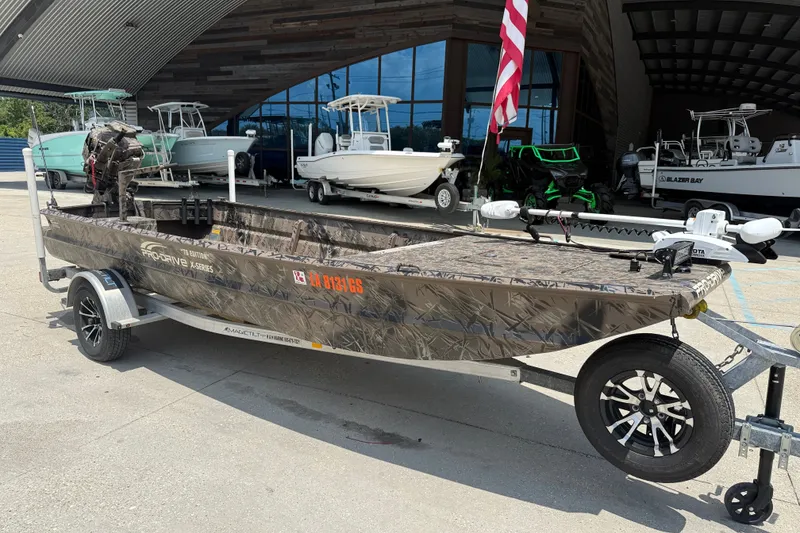 Slide: The Image of 2024 Pro-Drive 1854 SBX TD boat on trailer, camo design, parked outside dealership. - 2