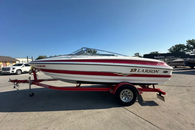 Slide: The Image of 2004 Larson SEi 190 boat on trailer, red and white design, parked outdoors. - 3