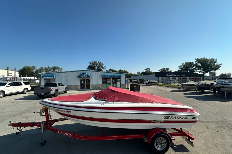 Slide: The Image of 2004 Larson SEi 190 boat with red cover on trailer, parked at dealership. - 4