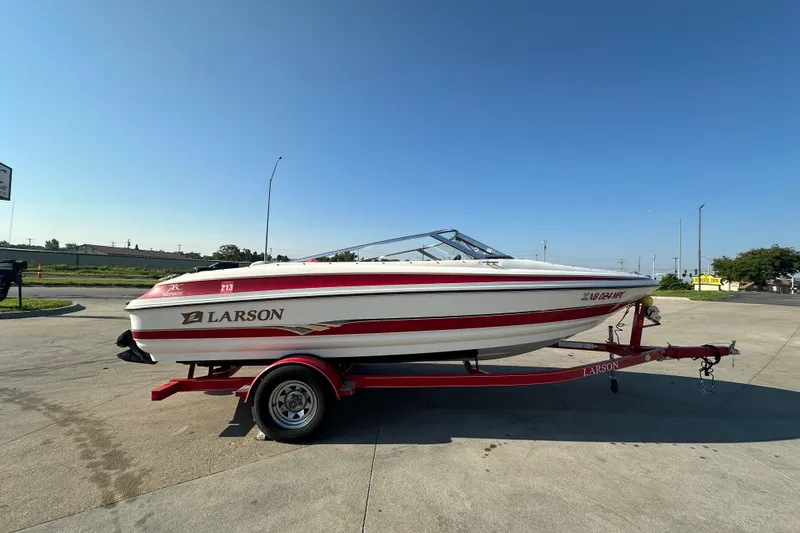 The Image of 2004 Larson SEi 190 boat on trailer, red and white design, parked outdoors. - 0