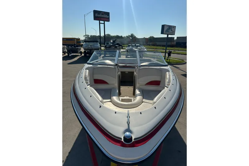 Slide: The Image of 2004 Larson SEi 190 boat with red accents, parked outdoors under clear sky. - 10