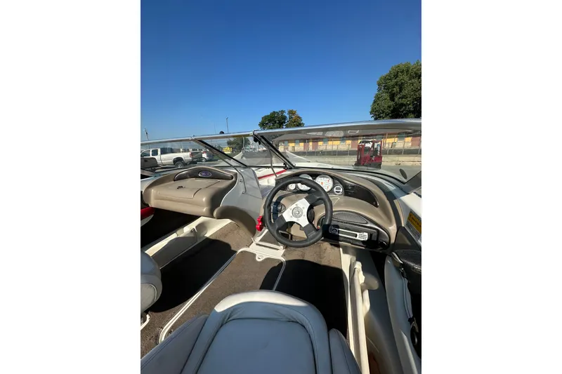 Slide: The Image of 2004 Larson SEi 190 boat interior with steering wheel and dashboard under clear blue sky. - 8