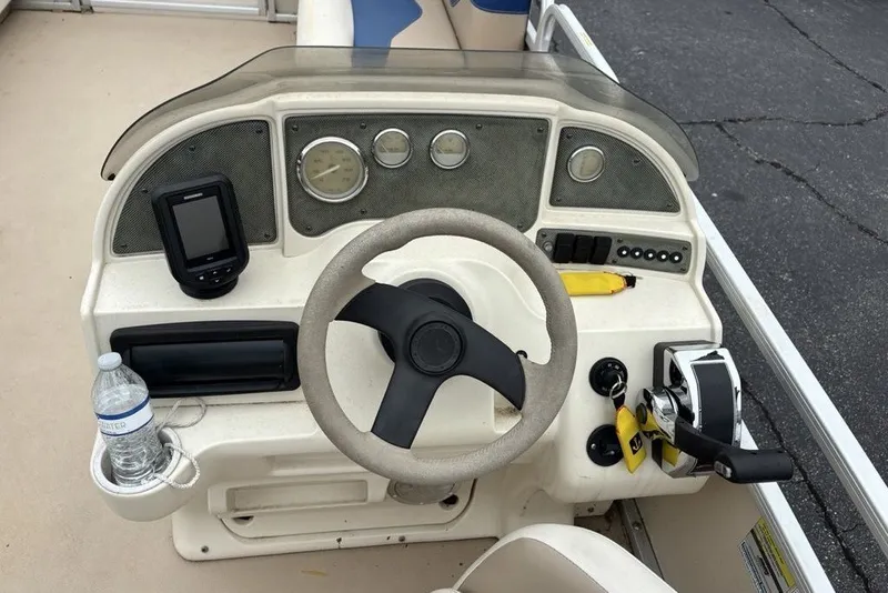 Slide: The Image of 2015 Godfrey Sweetwater boat dashboard with steering wheel, controls, and a water bottle. - 15