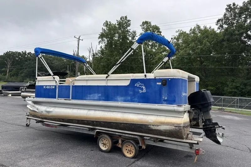 Slide: The Image of 2015 Godfrey Sweetwater pontoon boat with blue canopy on a trailer, parked outdoors. - 14