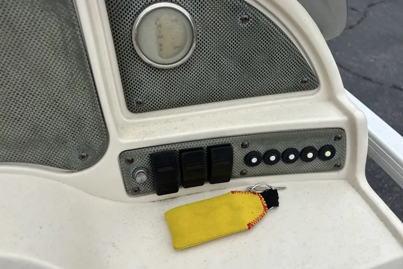 Slide: The Image of Control panel of a 2015 Godfrey Sweetwater boat with switches and a yellow key fob. - 17