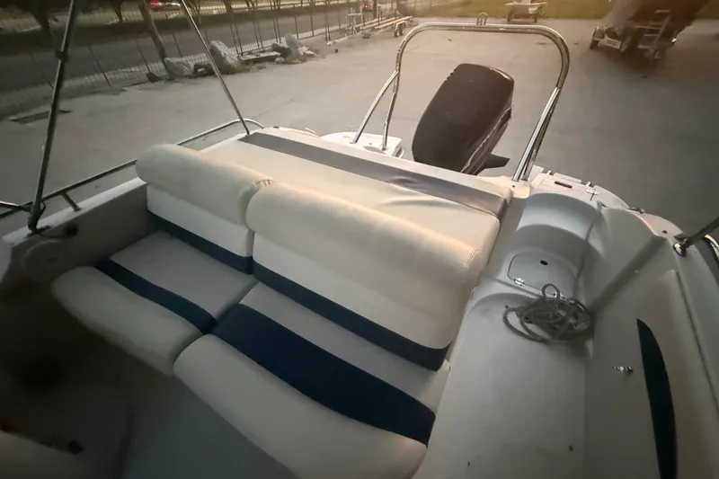 Slide: The Image of 2005 Starcraft SD 201 boat interior with cushioned seating and motor, docked outdoors. - 16