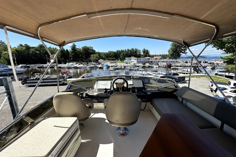 Slide: The Image of 2014 Marquis 420 Sport Bridge yacht interior with marina view, featuring helm and seating area. - 16
