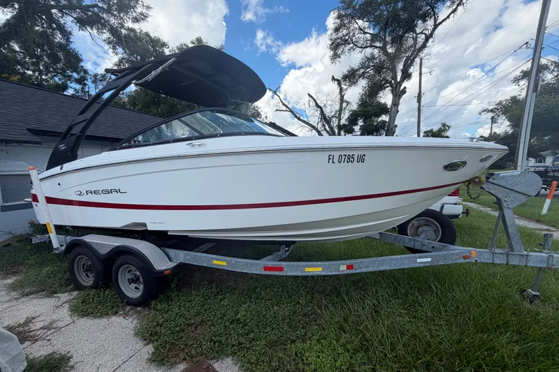 The Image of 2022 Regal LS2 boat on trailer, white with red stripe, parked outdoors. - 0