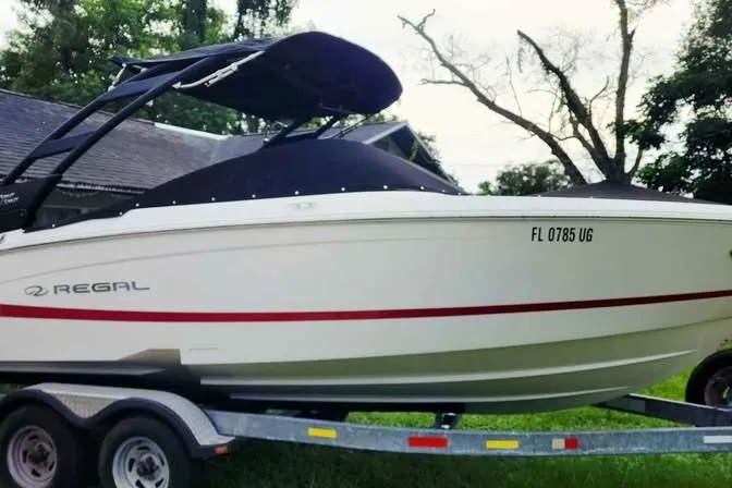 Slide: The Image of 2022 Regal LS2 boat on trailer, white with red stripe, parked outdoors. - 3