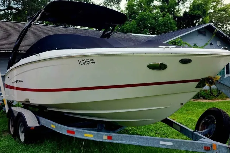Slide: The Image of 2022 Regal LS2 boat on trailer, white with red stripe, parked on grass. - 1