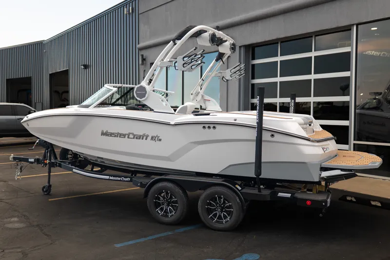 Slide: The Image of 2027 MasterCraft NXT20 boat on trailer outside a modern building. - 6