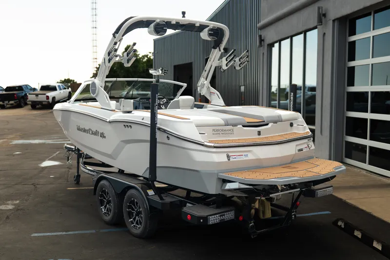 Slide: The Image of 2027 MasterCraft NXT20 boat on trailer, parked outside a modern building. - 7
