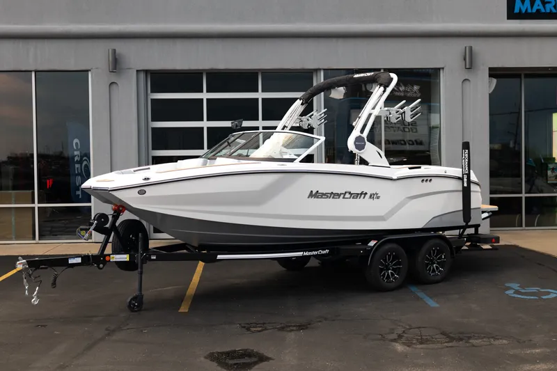 Slide: The Image of 2027 MasterCraft NXT20 boat on trailer, parked outside a showroom. - 2