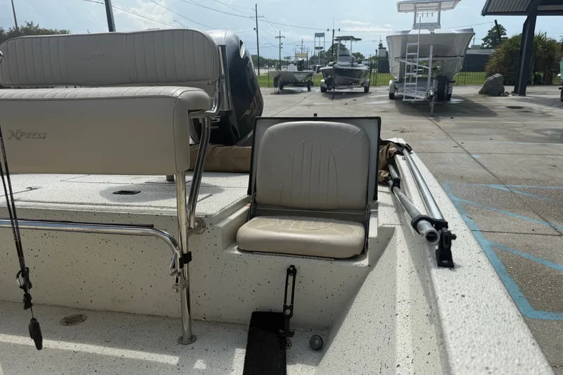 Slide: The Image of 2018 Express 20 boat interior with seating and fishing rod holders in a parking area. - 19