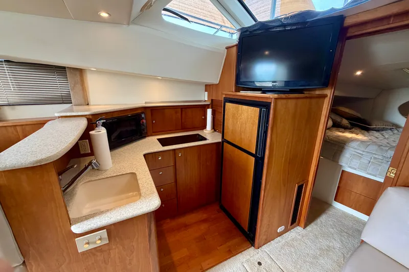 Slide: The Image of 2002 Silverton 330 Sport Bridge interior with kitchenette, TV, and cozy sleeping area. - 27