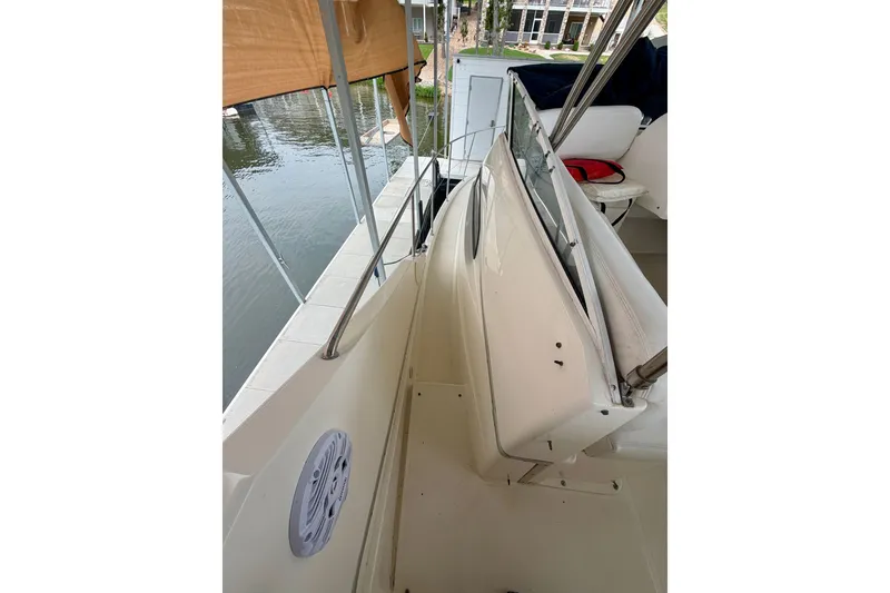 Slide: The Image of 2002 Silverton 330 Sport Bridge boat deck with railing and seating, docked by water. - 20