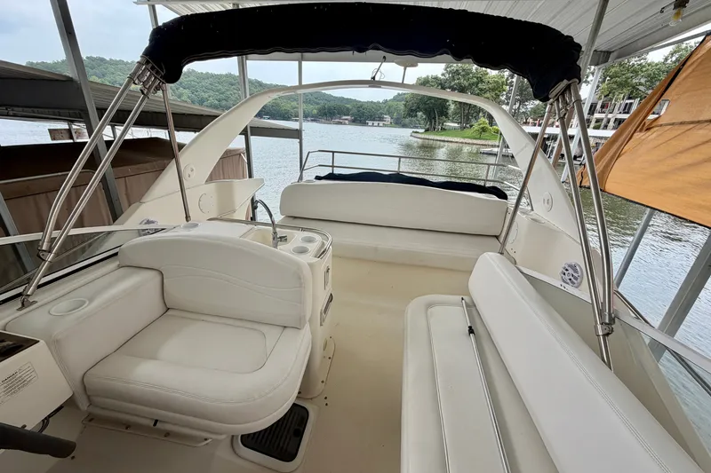 Slide: The Image of 2002 Silverton 330 Sport Bridge interior with white seating, docked by a scenic lake. - 19