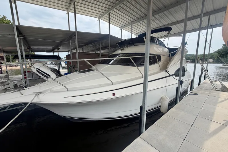 Slide: The Image of 2002 Silverton 330 Sport Bridge docked under a covered marina on a calm lake. - 2