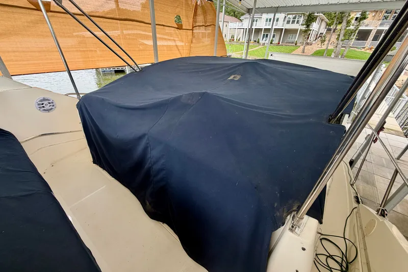 Slide: The Image of 2002 Silverton 330 Sport Bridge covered with a navy tarp, docked near waterfront homes. - 37