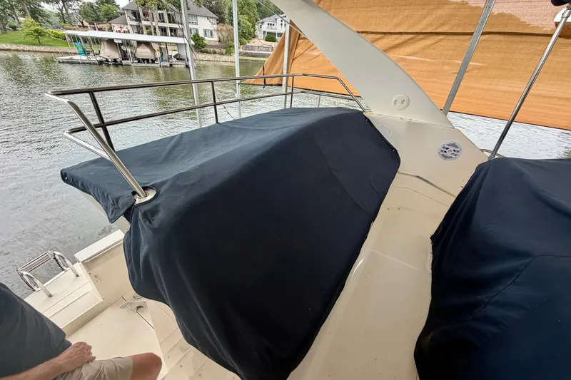 Slide: The Image of 2002 Silverton 330 Sport Bridge boat with covered seating area on a calm waterfront. - 38