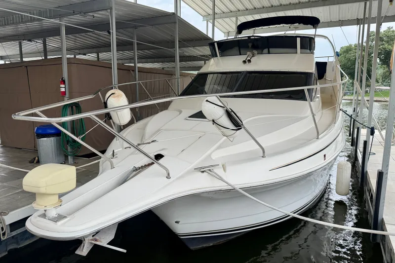 Slide: The Image of 2002 Silverton 330 Sport Bridge docked under a covered marina, showcasing sleek design and spacious deck. - 4